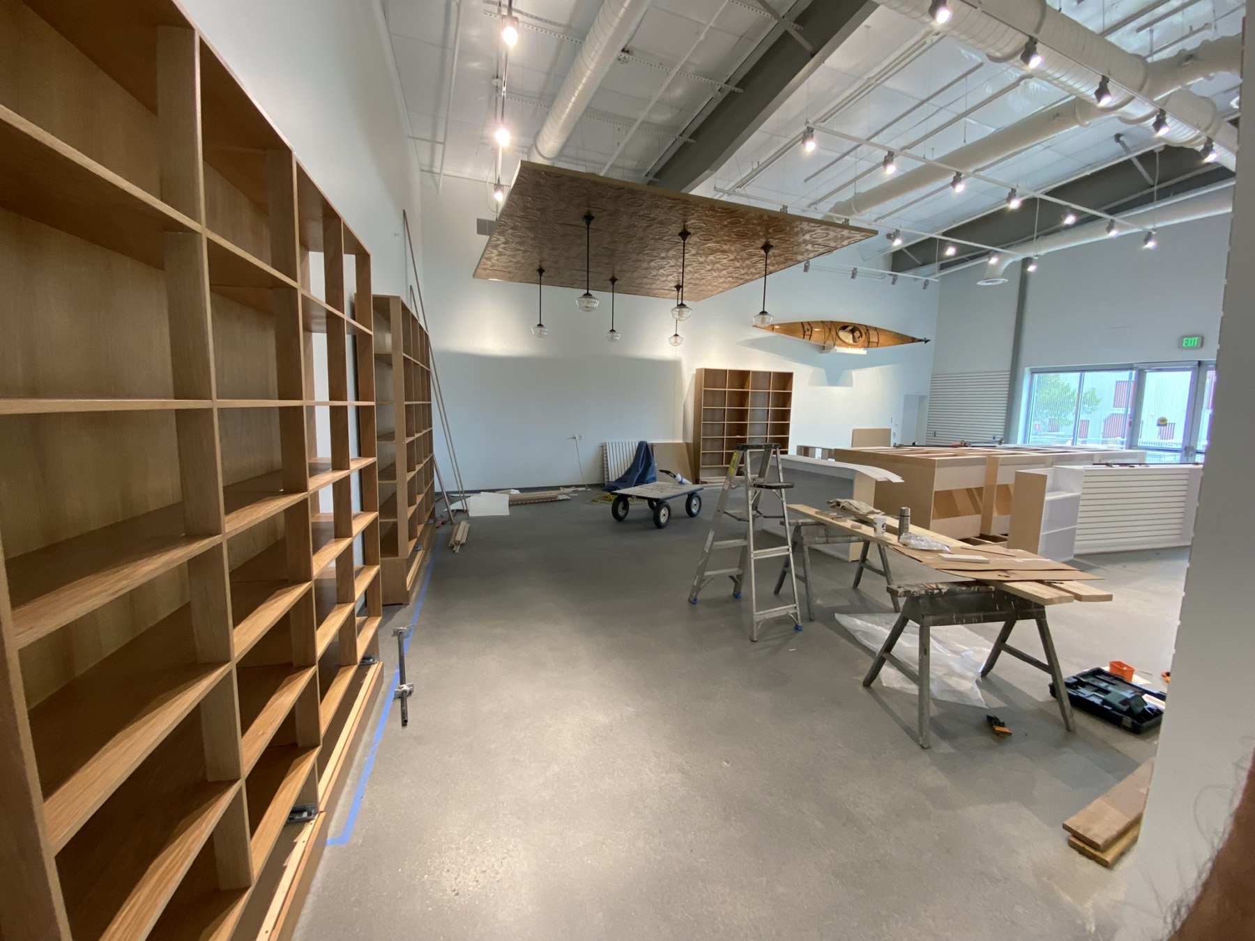 Museum store millwork installation in progress with oak shelving and decorative ceiling panel