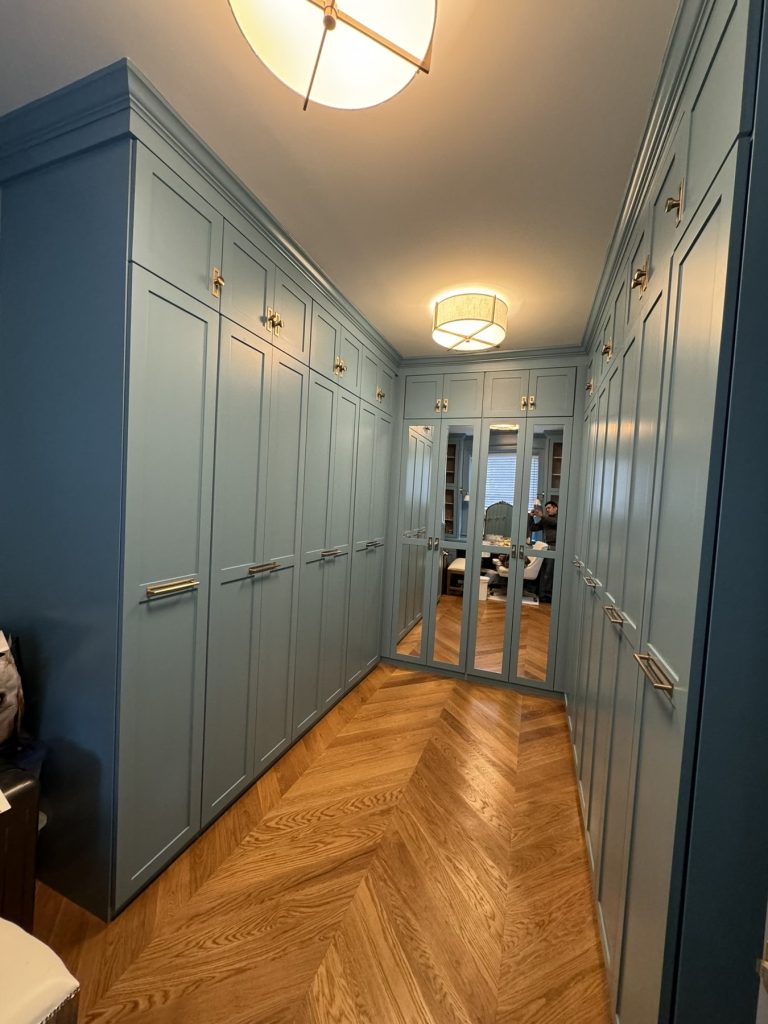 Custom sage blue walk-in closet gallery hall with floor-to-ceiling wardrobe doors and herringbone floor