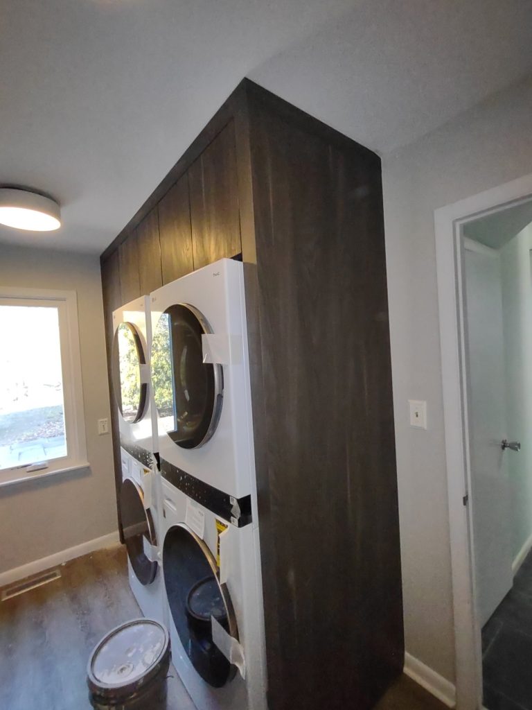 Stacked laundry units in custom cabinetry surround