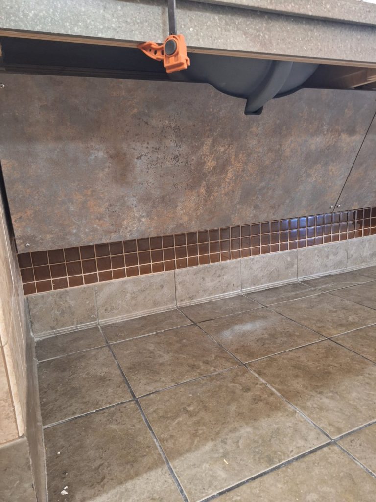 Angled under-sink access panel in shop-pressed laminate providing ADA knee clearance
