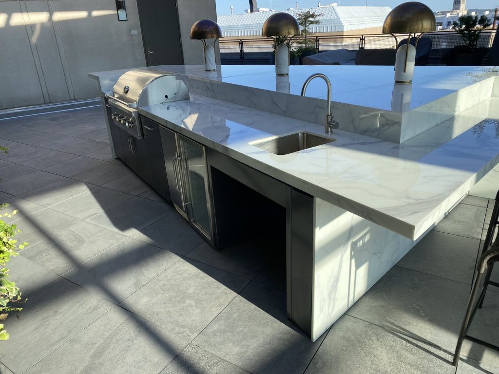 Outdoor kitchen island with grill, beverage center, and glass-door refrigerator