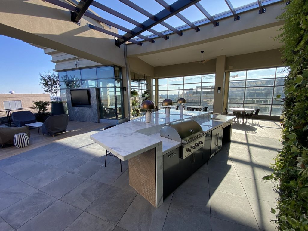 Covered rooftop lounge with stone media wall, bar seating, and living green wall