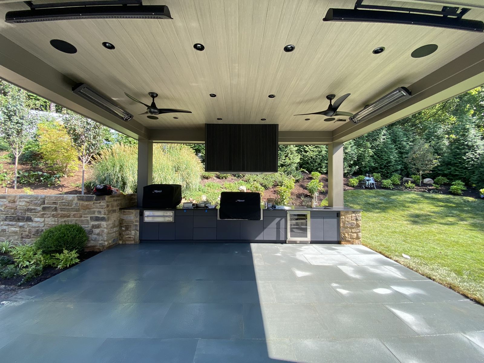 Outdoor kitchen cabinetry by SMFW in a covered pavilion with grills, refrigeration, and stone surround