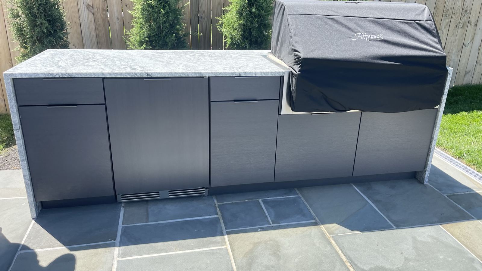 Exterior-grade stone countertop with waterfall edge on outdoor cabinetry