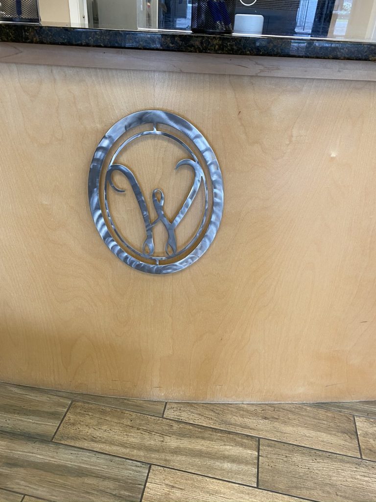 Brushed steel W logo medallion mounted on curved maple desk front